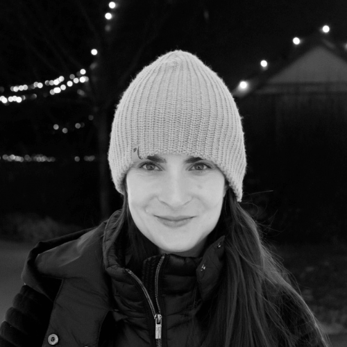 Paige smiling in a black and white portrait wearing a beanie and coat